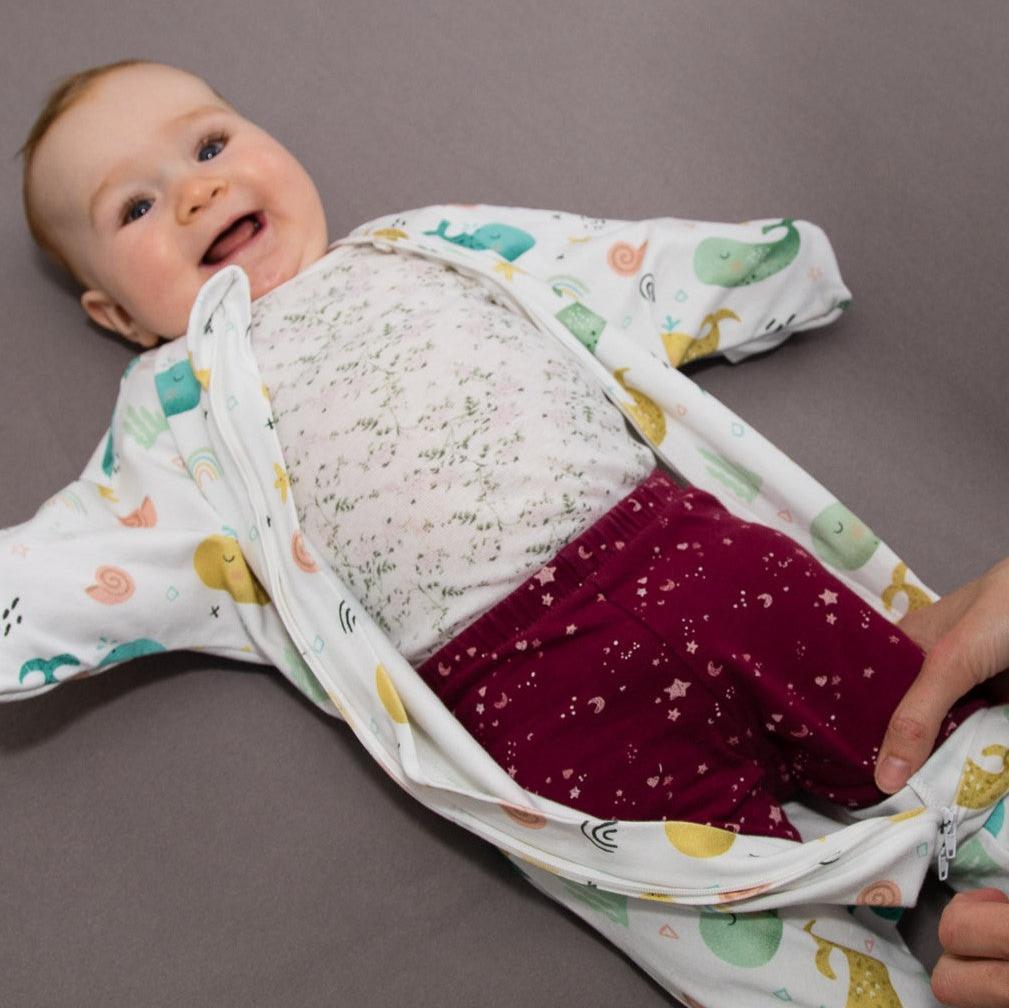 Wombi Schlafsack wird mithilfe des Zwei-Wege-Reißverschlusses einem Baby angezogen