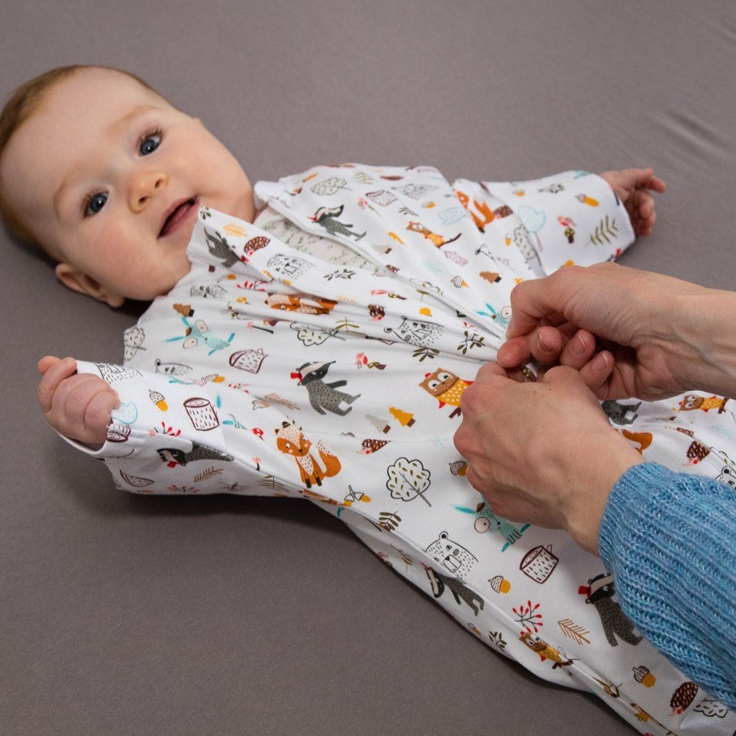 Wombi Schlafsack wird mithilfe des Zwei-Wege-Reißverschlusses einem Baby angezogen