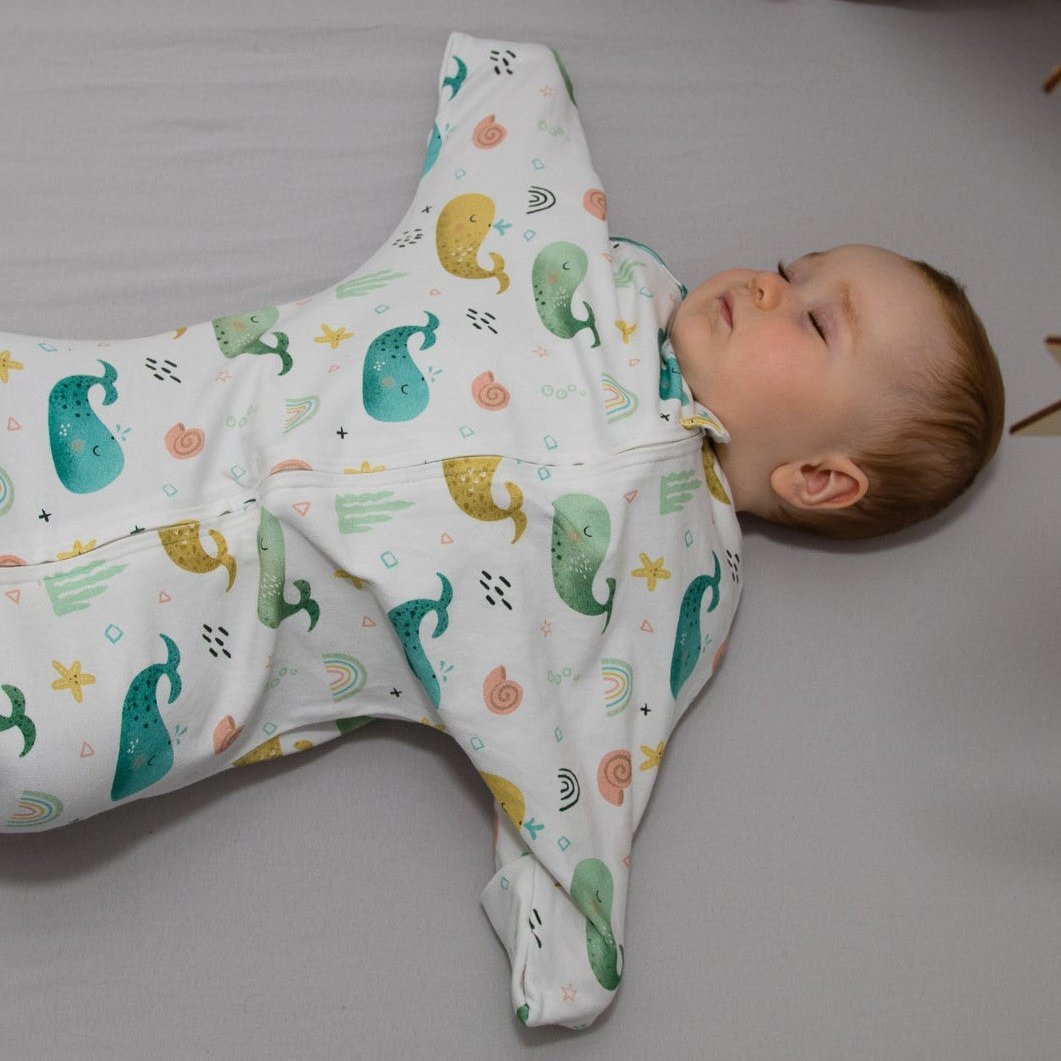 Baby liegt schlafend mit Wombi Schlafsack im Bett