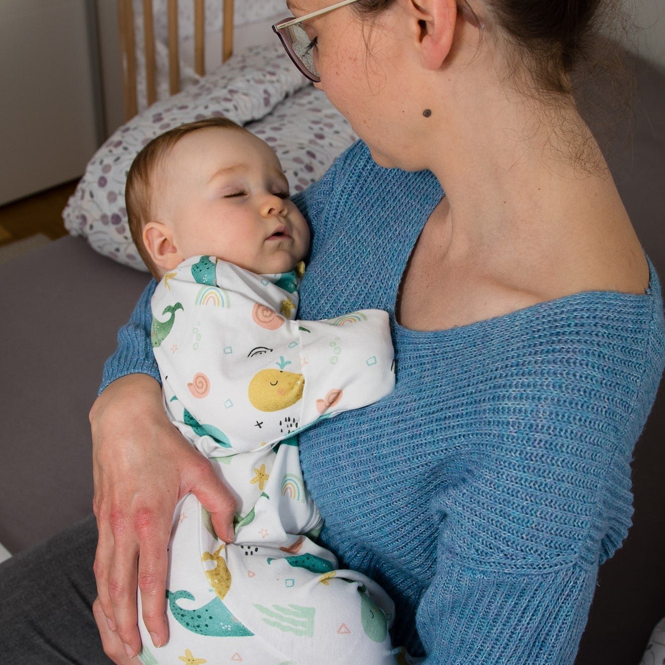 Baby wird in den Armen der Mutter gehalten und schläft