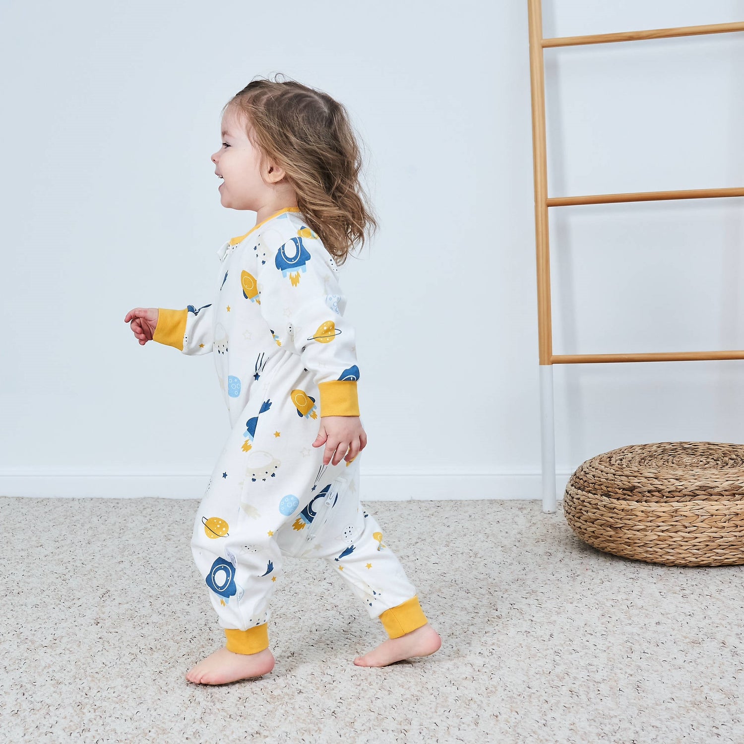 Kind läuft lachend mit Schlafanzug durchs Zimmer