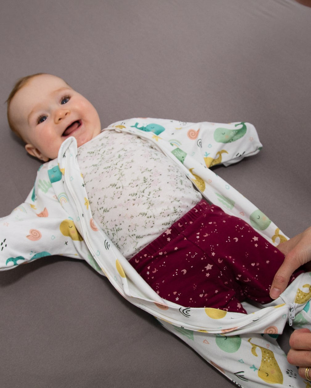 Wombi Schlafsack wird mithilfe des Zwei-Wege-Reißverschlusses einem Baby angezogen