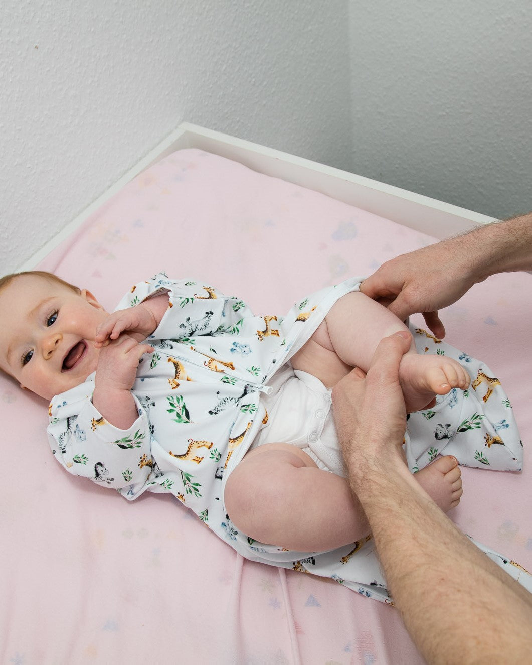 Baby wird angezogen mit Vorteil des Zwei-Wege-Reißverschlusses