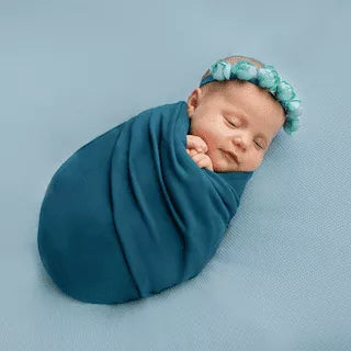 Baby schläft friedlich in einem Pucktuch eingewickelt