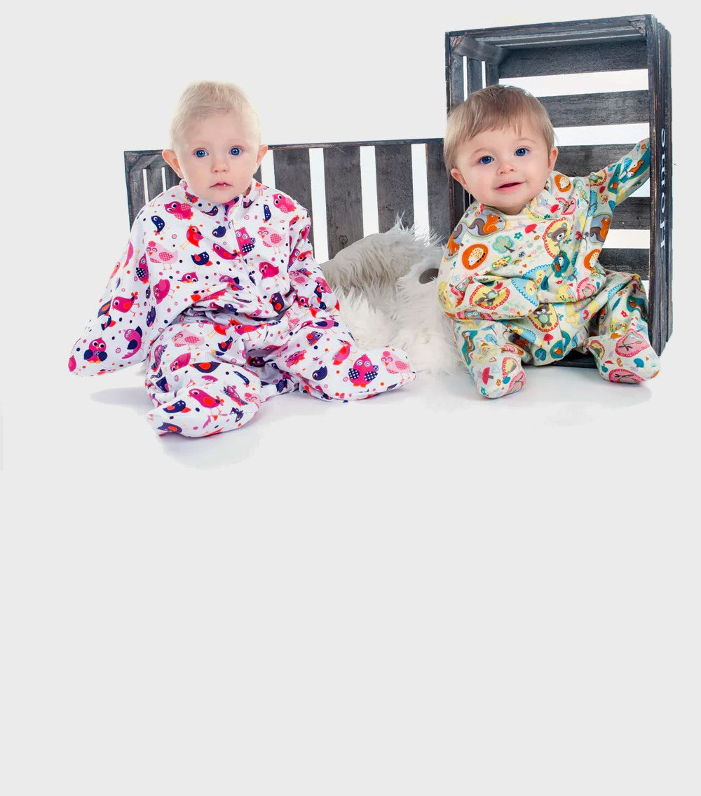 Zwei Babys im Wombi Schlafsack sitzen vor zwei Kisten  